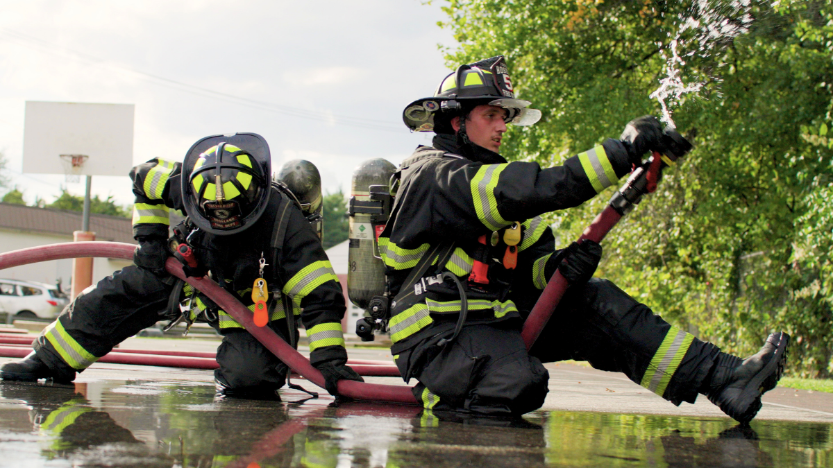 Firefighters advancing a hose line in structural turnout gear, demonstrating how mobility and unrestricted movement support performance during fireground operations.